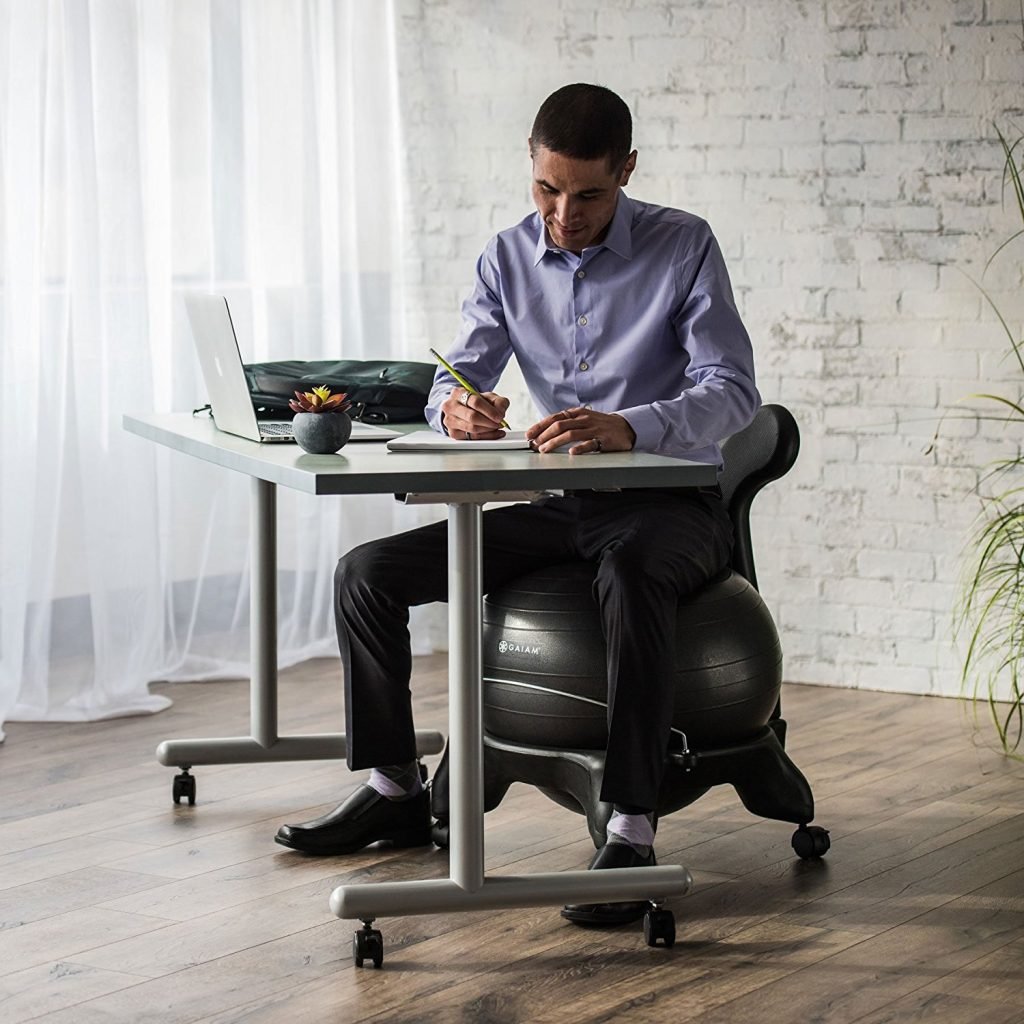 man sitting on the gaiam yoga ball while doing work