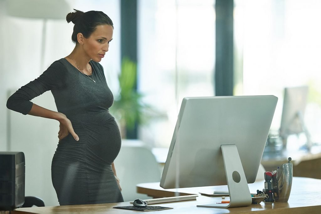 pregnant business woman standing up working in an office