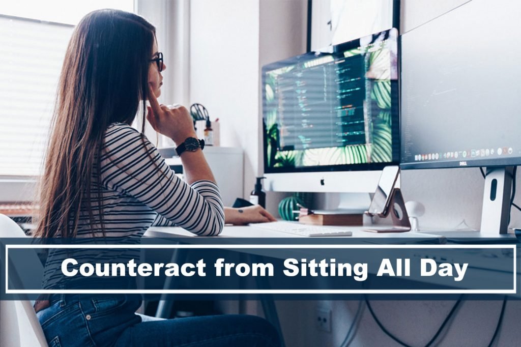 woman sitting in front of dual monitor screens