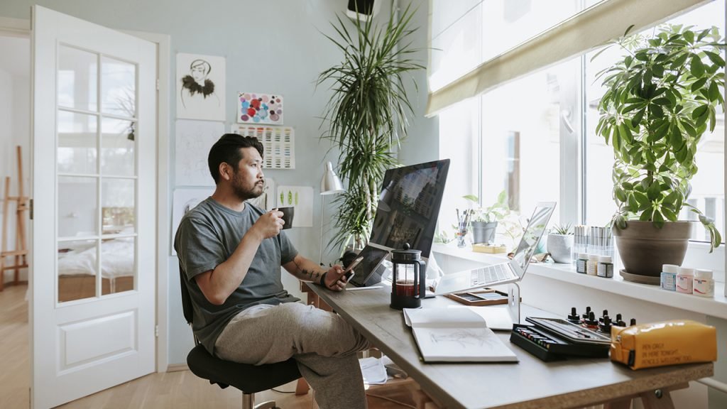 man drinking coffee working from home with plants